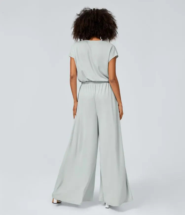 Neformální overal s V-výstřihem, širokými plisovanými nohavicemi, krátkým rukávem, boční kapsou a splývavou texturou